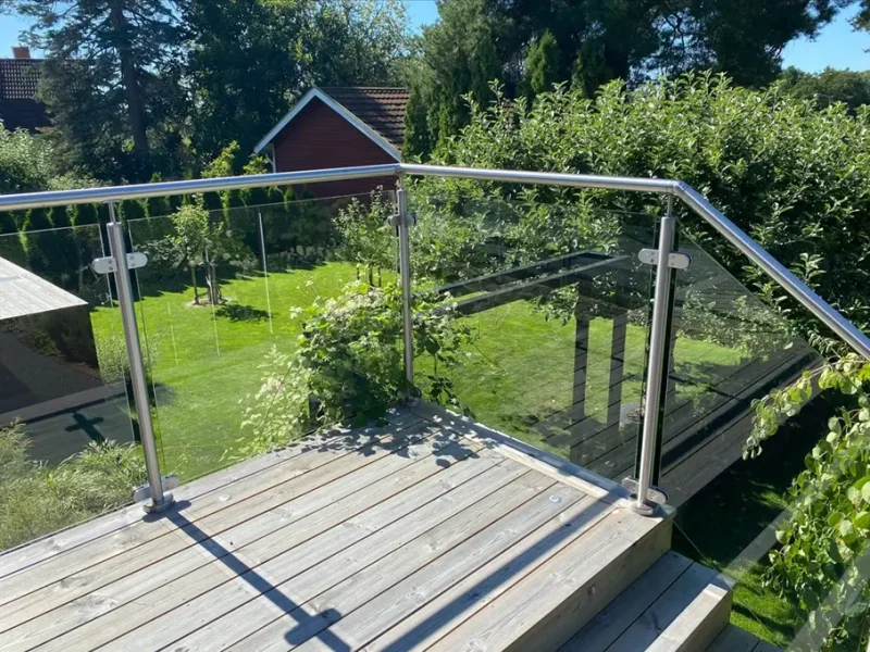 Glasräcke med stolpar och handledare i borstat rostfritt stål.